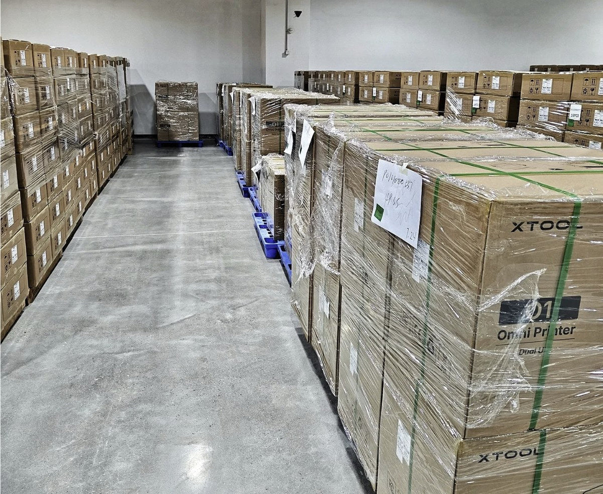 Palés de cajas de la xTool O1 Omni Dual UV precintadas en un almacén, listas para envío