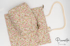 Neceser y bolsa de algodón con estampado floral en tonos rosas y verdes sobre fondo blanco.