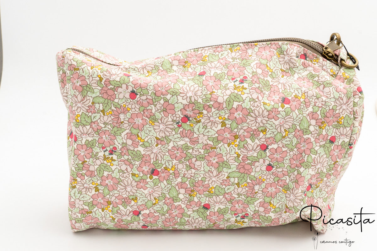 Detalle de neceser floral rosa con cierre de cremallera metálica y tirador de tela.