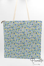 Bolsa de algodón con estampado floral azul y blanco con asas largas de cuerda.
