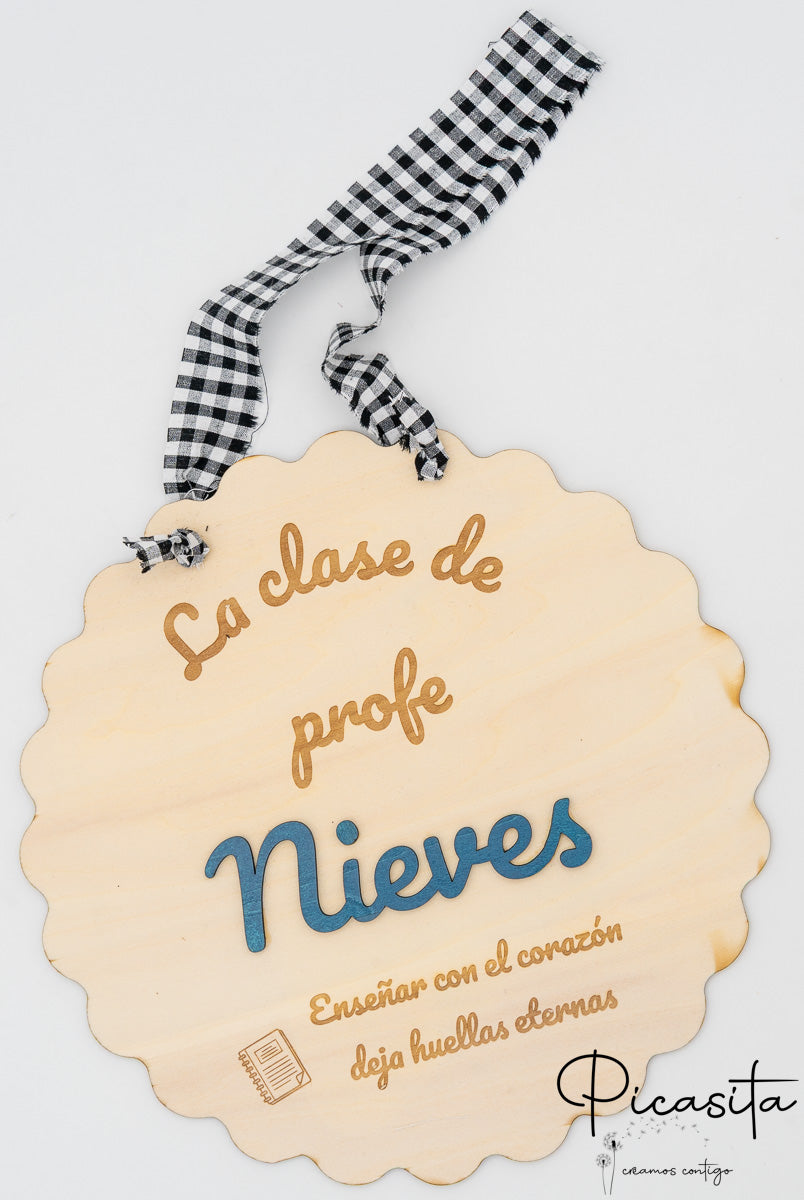 Cartel de madera festoneado con nombre Nieves en relieve azul y cinta de cuadros negros y blancos.
