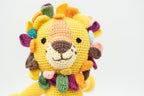 Primer plano de la cara de un león de crochet amarillo con melena de pétalos coloridos.
