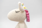 Detalle lateral de la cabeza de un unicornio tejido con ojos cerrados y melena rosa.