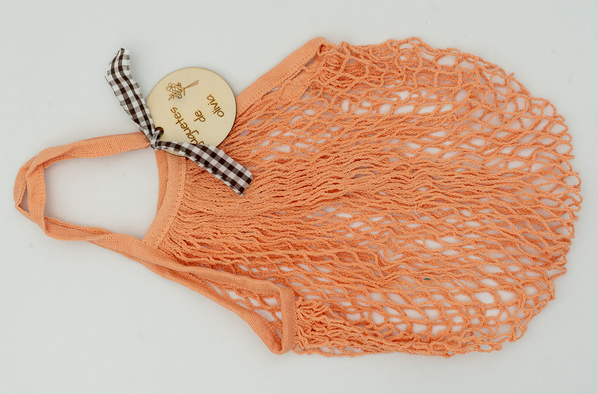 Bolsa de playa antiarena en color naranja con accesorio decorativo de madera circular.
