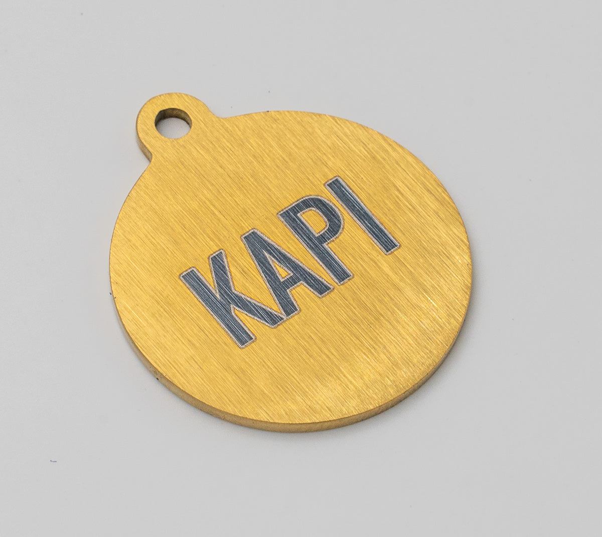 Reverso de chapita para perro dorada de 30 mm con el nombre KAPI grabado a láser