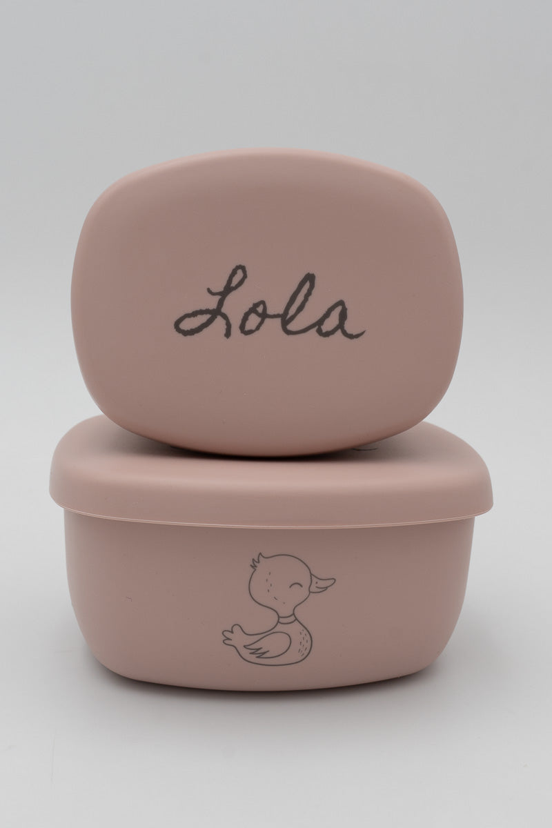 Dos tuppers rosa apilados con el nombre Lola y dibujo de pato