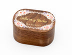 Ovale Ringbox aus Nussbaum mit farbig bedruckten Blumen und den Namen Valeria und Nacho