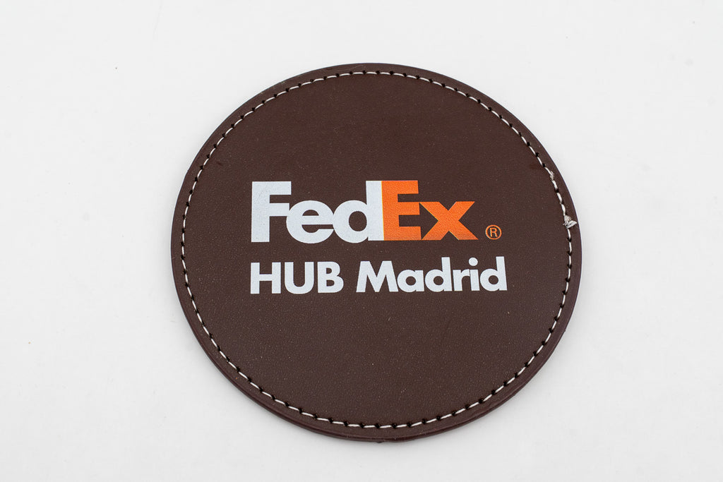 Runder brauner Untersetzer mit farbigem FedEx-Logo.
