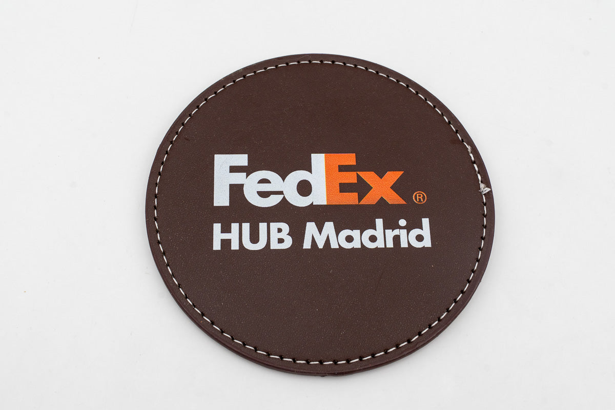 Runder brauner Untersetzer mit farbigem FedEx-Logo.