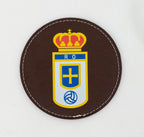 Runder brauner Untersetzer mit farbigem Fußballwappen.