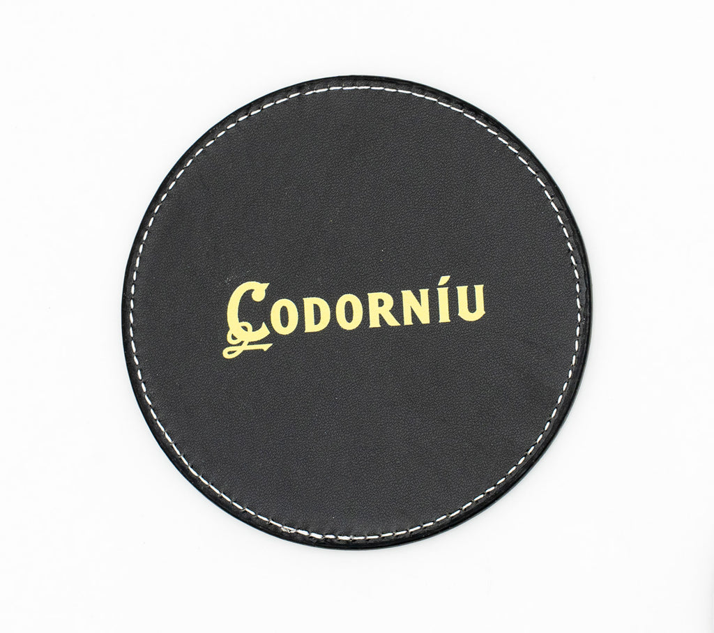Runder schwarzer Untersetzer mit goldfarbenem Codorníu-Logo.