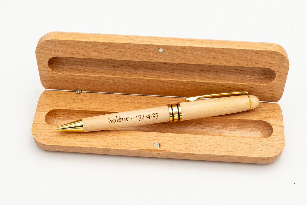 Offenes Etui mit hellem Holz-Kugelschreiber mit Kappe und goldfarbenen Details.