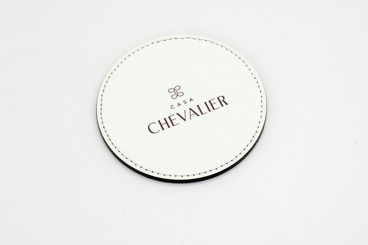 Runder weißer Untersetzer mit grauem Chevalier-Logo.