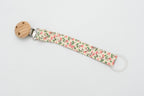 Schnullerband aus Stoff mit kleinen rosa Blumen, grünen Blättern und rundem Holzclip