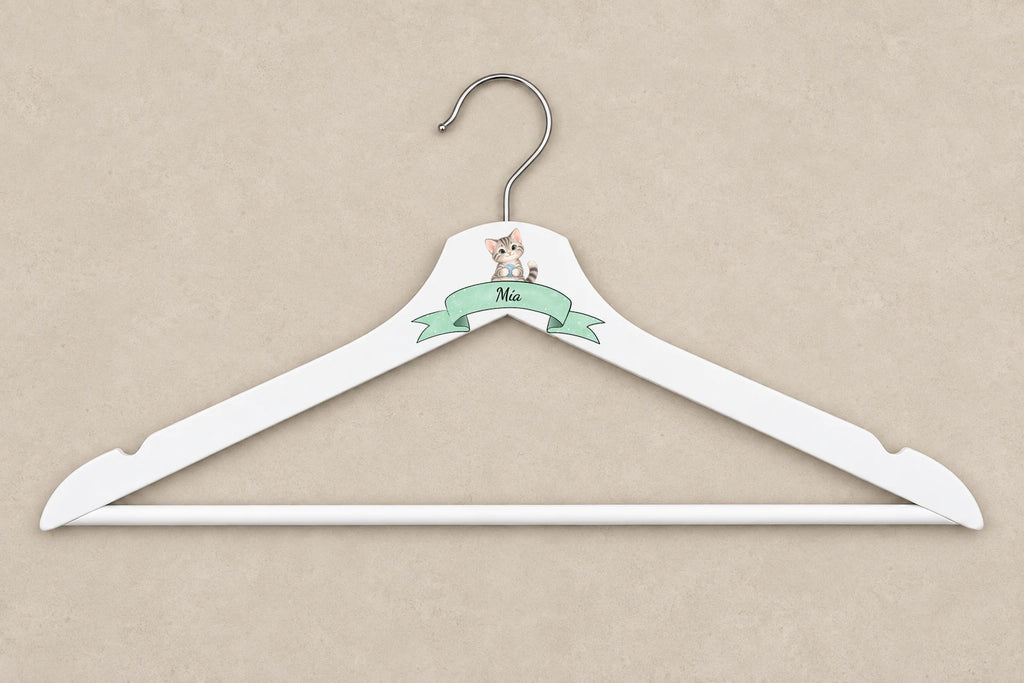 Percha adulta blanca con gatito, cinta menta y nombre Mía sobre mesa beige