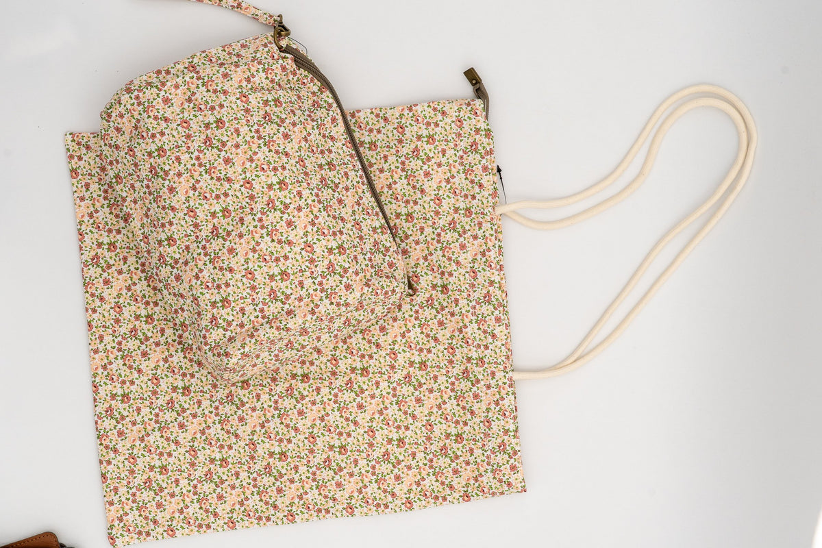 Kulturbeutel auf Stofftasche mit pfirsichfarbenen Blumen und grünen Blättern