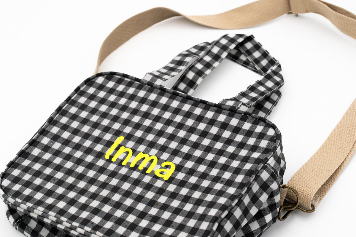 Wechselwäsche-Tasche aus schwarzem Vichy-Karo mit dem Namen Inma in gelbem Vinyl und Schultergurt