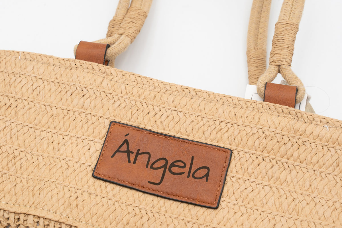 Patch aus Kunstleder an einer Raffia-Tasche, graviert mit dem Namen Ángela