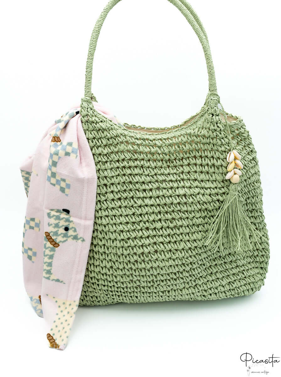 Bolso hobo verde oliva trenzado con borla de conchas marinas y pañuelo geométrico rosa.