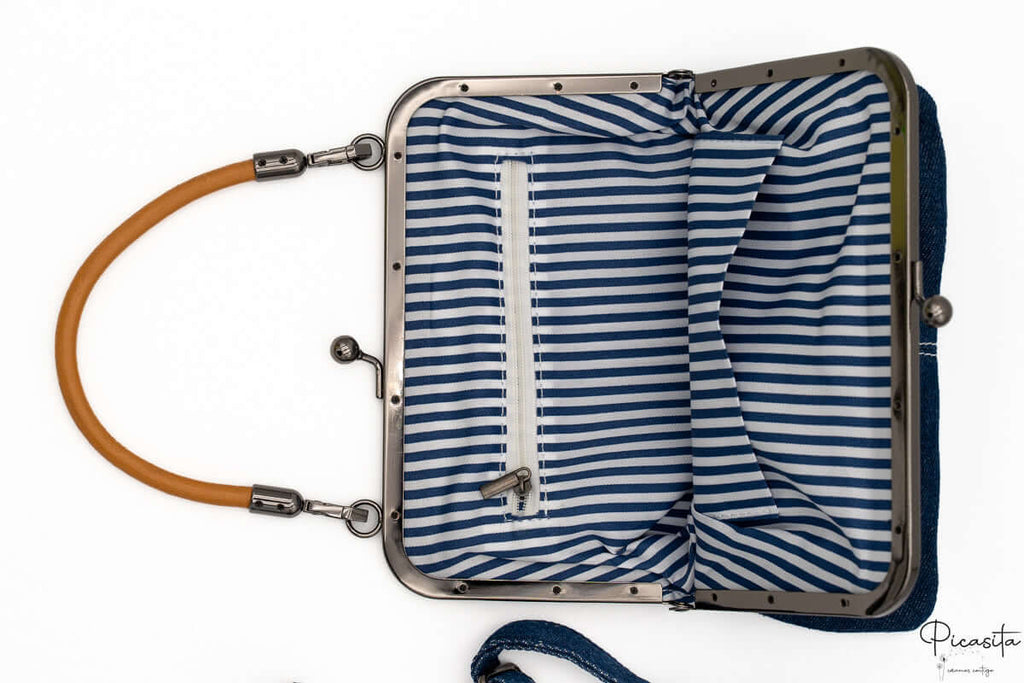 Interior de bolso con forro de rayas blancas y azules y bolsillo interno con cremallera.