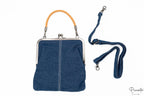 Bolso de mano denim con cierre metálico de boquilla y asa corta de color ocre.