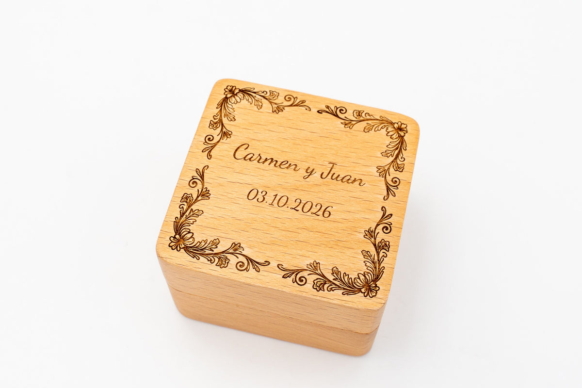 Quadratische Ringbox aus Buche, lasergraviert, mit Blumenrand, den Namen Carmen und Juan und dem Datum
