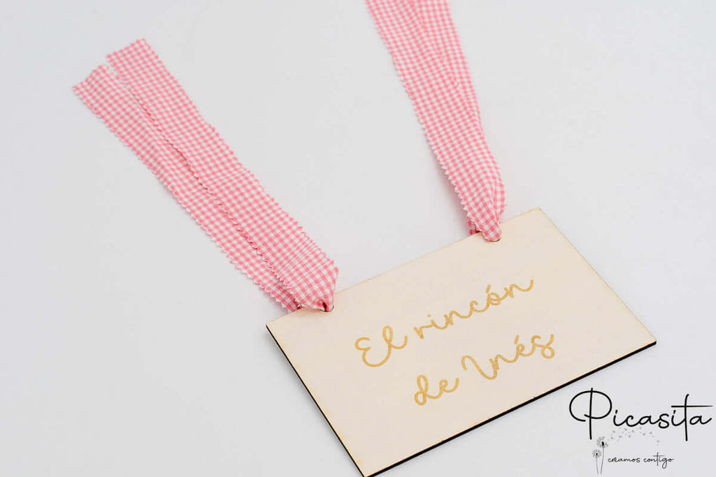 Cartel de madera con nombre Inés y cintas de tela de cuadros vichy rosas.
