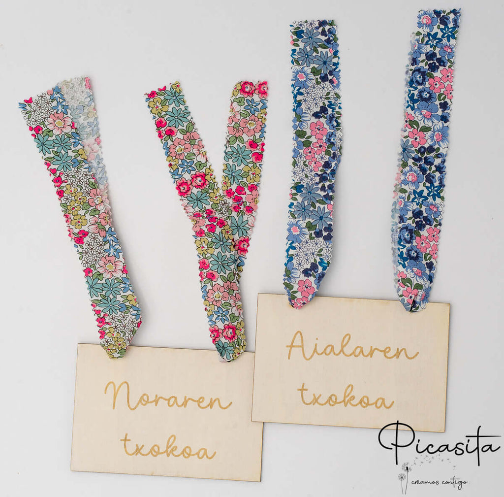 Dos carteles de madera personalizados para Nora y Aiala con diferentes cintas florales.