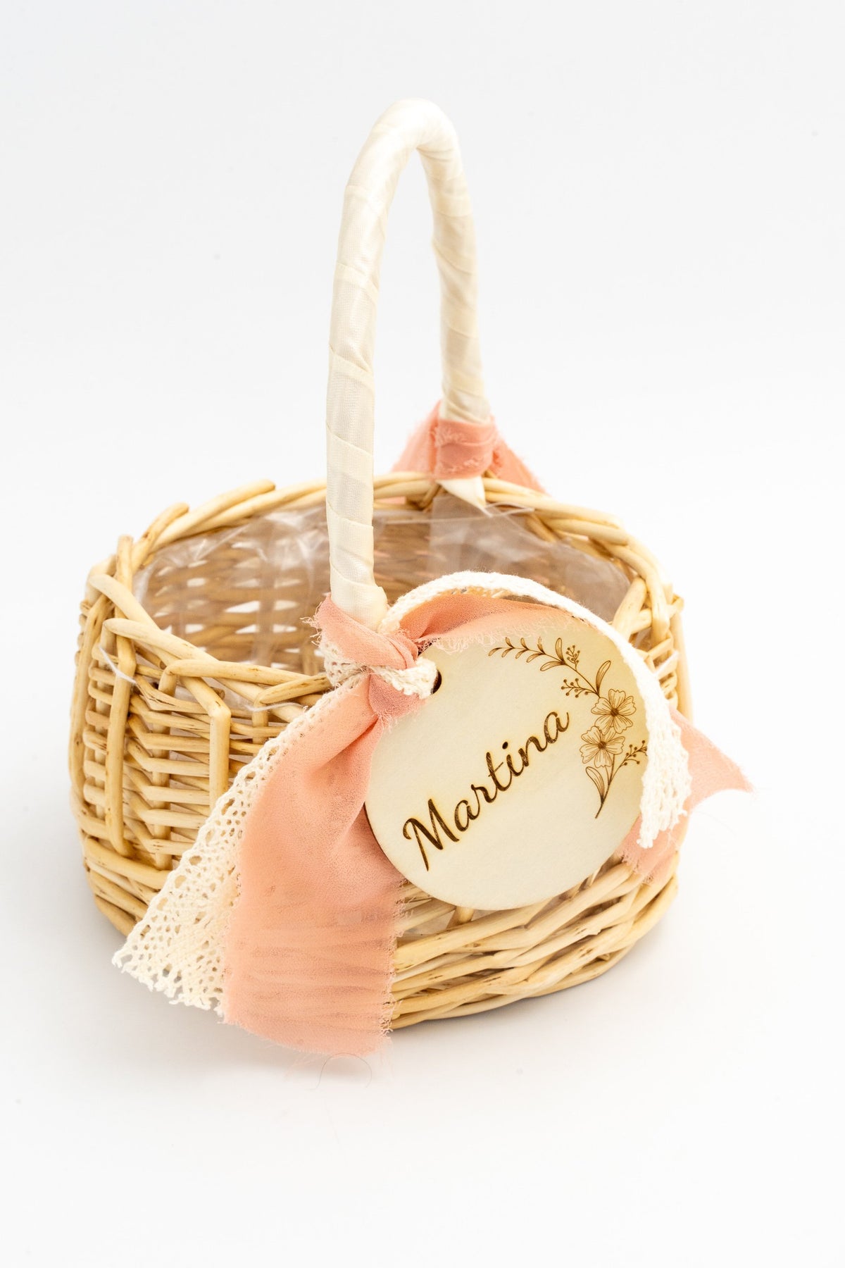 Rattankorb mit cremefarben umwickeltem Henkel und lachsfarbener Gazeschleife.