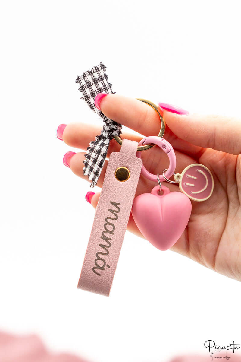 Primer plano de llavero rosa para mamá con detalles dorados y charms decorativos sobre fondo blanco.