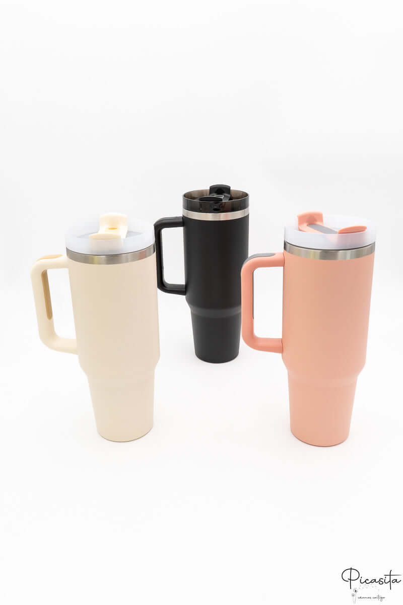 Tres vasos térmicos con asa en colores crema, negro y salmón sobre fondo blanco.