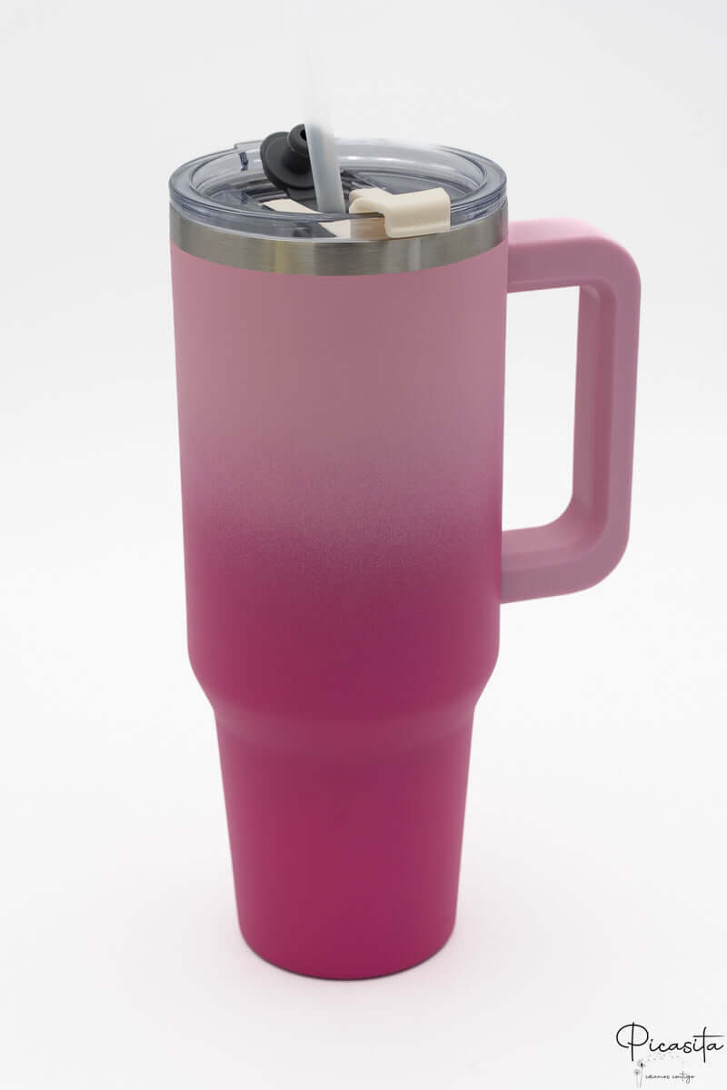 Termo con degradado de rosa claro a fucsia con asa y tapa transparente.