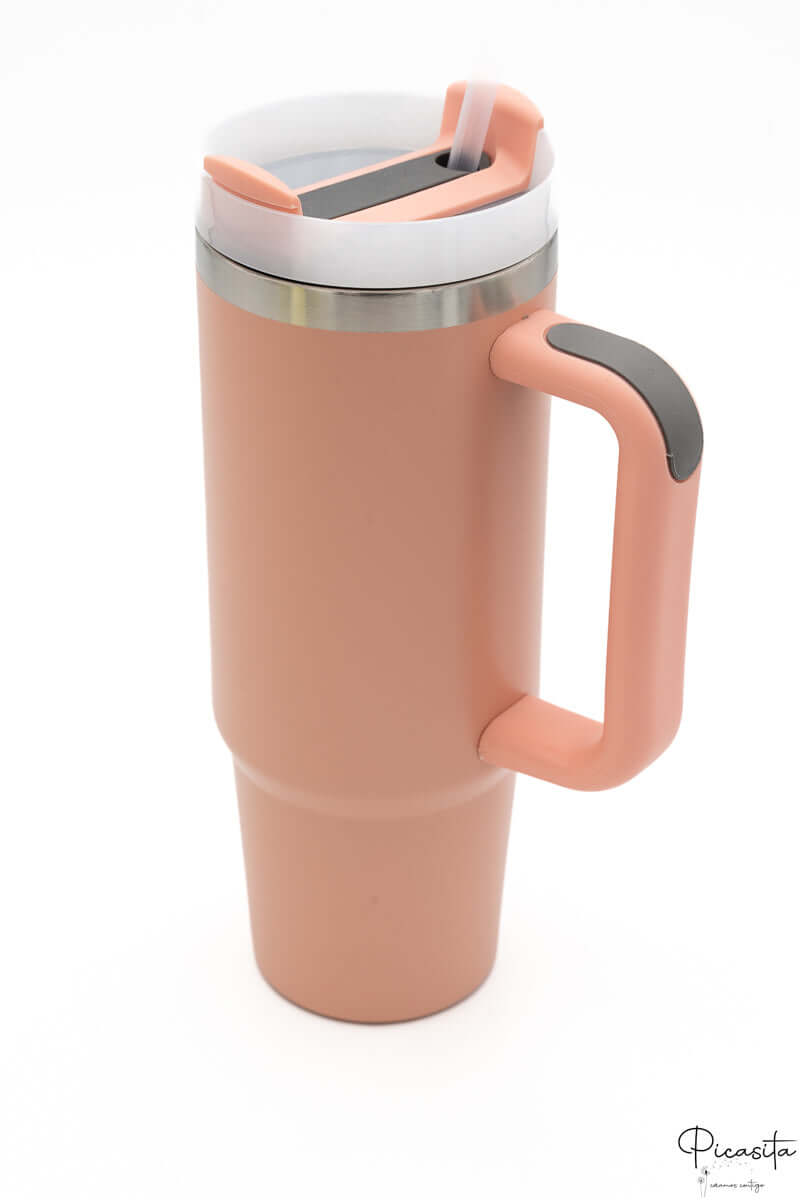 Vaso térmico color salmón con asa y tapa con detalle en gris oscuro.