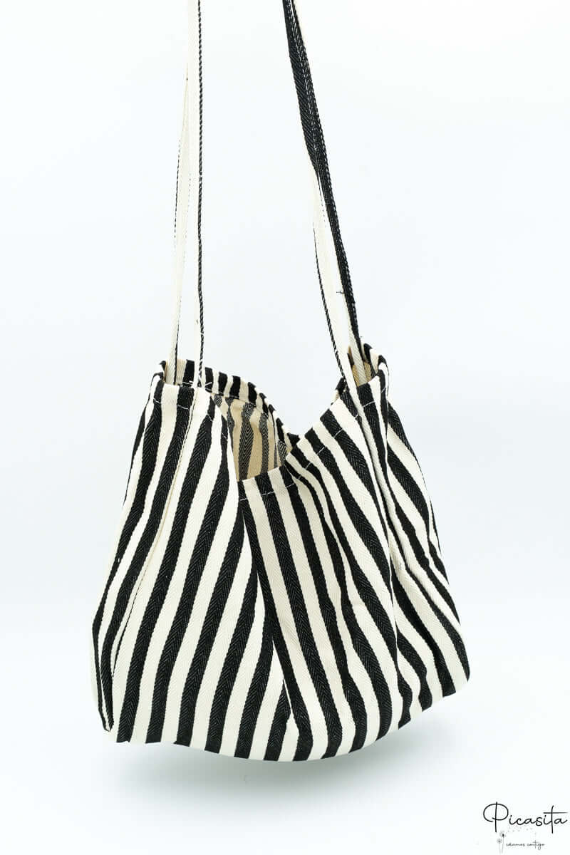 Bolsa de tela con diseño de rayas negras y blancas colgada de sus asas.