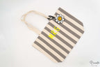 Bolso para piscina con rayas grises y blancas decorado con un charm de margarita.